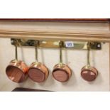 Set of Four Small Copper Graduating Pans with Brass Handles and Brass Hanging Rail