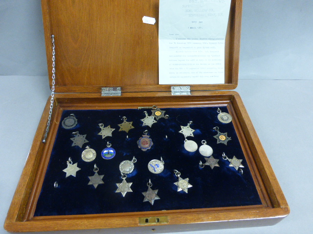 Various silver and enamel swimming and other sports badges encased in a mahogany box