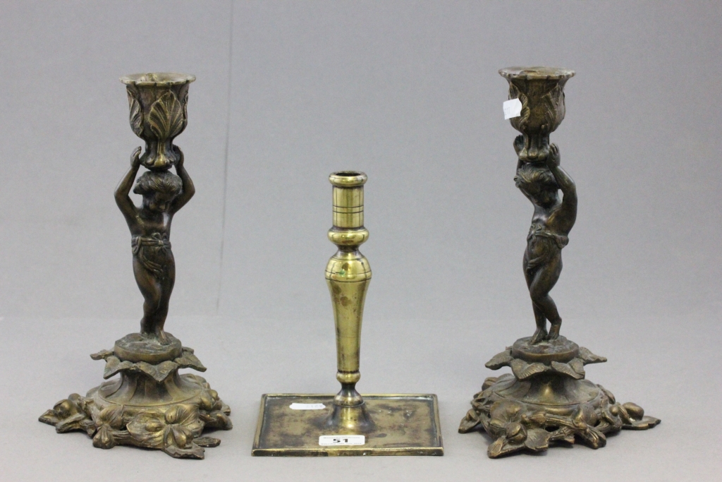 A pair late 19th century brass and bronze figural candlesticks; each in the form of a cherub holding