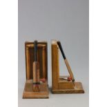 A pair of 1930s oak book ends; each in the form of cricket stumps with a bat learning and ball the