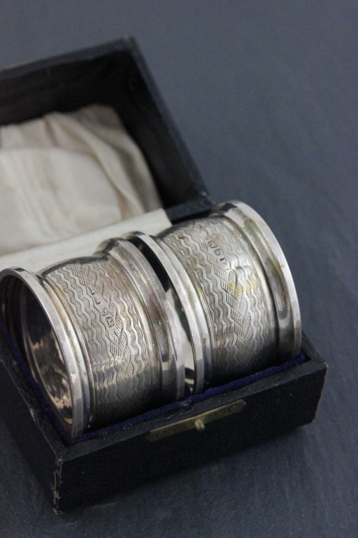 A cased pair of hallmarked napkin rings; William Aitken: Birmingham 1899; with engine turned