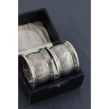 A cased pair of hallmarked napkin rings; William Aitken: Birmingham 1899; with engine turned