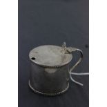 A George V hallmarked silver mustard pot; with reeded edges, 'C' scroll handle and thumb piece;