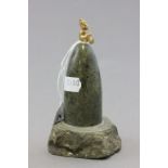 A green hard stone; of conical shape; surmounted with a small gilt pixie