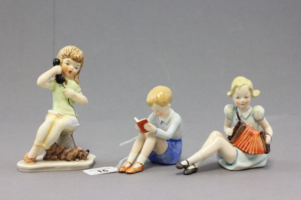 Three Goebel porcelain figures of children comprising; a boy reading a book; impressed to 216 to