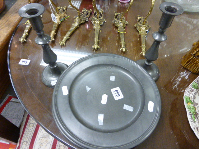 Eight various pewter plates together with a pair of pewter candlesticks