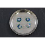 A silver and enamel dressing table trinket dish, of circular form, embossed with four flowerheads,