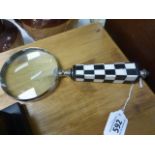 A large hand held magnifying glass with checkerboard handle