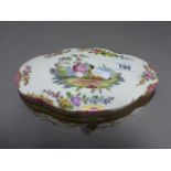 A large shaped ceramic box, hand decorated with a couple, floral sprays and a gilt rim, the base