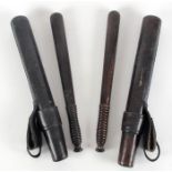 Two Police truncheons in leather uniform scabbards. Two early 20th century lignum vitae truncheons