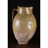 A Large Late 16th Century Earthenware Jug of baluster form with mottled green/ochre glaze,