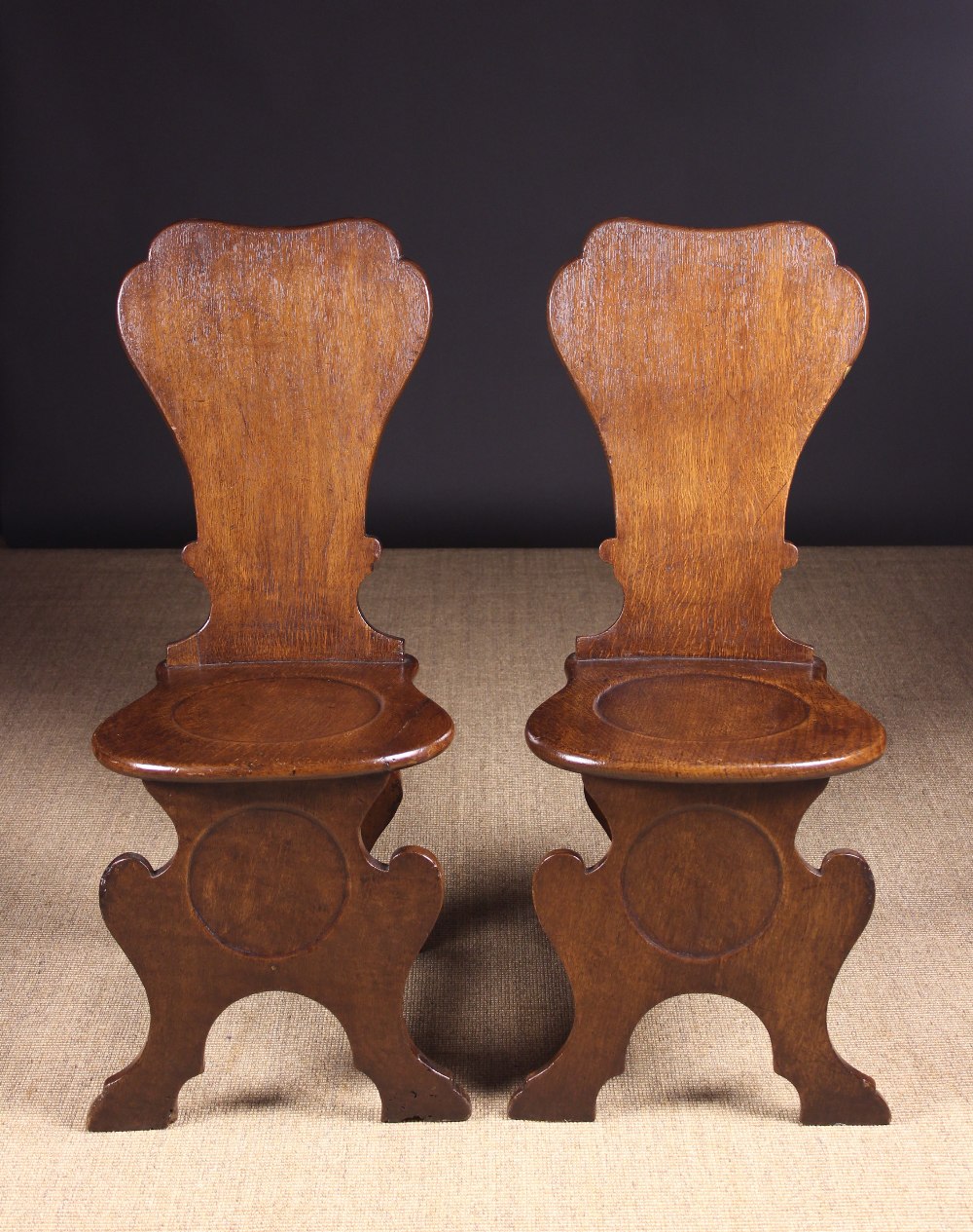 A Pair of George III Mahogany Planked Oak Hall Chairs of sgabello inspired design.