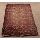 A Small Bokhara Rug with two rows of six Tekke guls and cruciform in a faded red ground in a banded