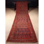 A Carpet Runner woven predominantly in claret,