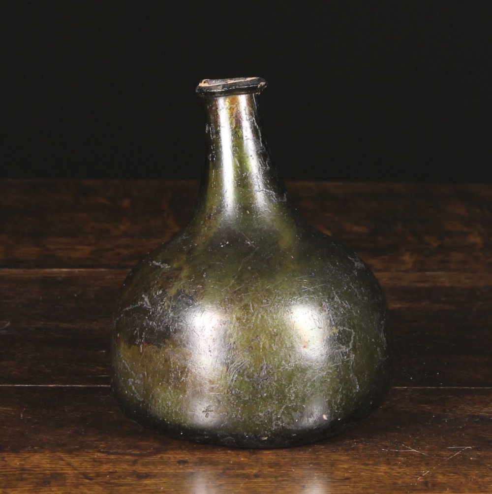 A 17th Century Iridescent Green Glass Onion Bottle with kick up base, 6½ ins (16.5 cms) in height.