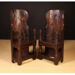 A Pair of Dug-out Armchairs. The high bowed backs hewn from hollowed tree trunks with winged sides.