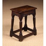 An 18th Century Oak Joint Stool having a moulded top above serpentine rails on rising baluster legs
