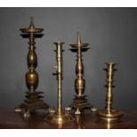 Four Candlesticks: A dark patinated bronze pricket candlestick with a knopped stem above a