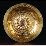 A 16th Century Brass Repoussé Alms Dish with a wrythen rosette centre boss and gadrooned sides,