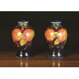 A Pair of Moorcroft Rising Baluster Vases decorated with Pomegranate design on a dark blue ground,