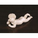 A Delightful 19th Century Ivory Carving of a naked, curly haired Cherub laid on his stomach,