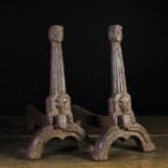A Pair of 16th/17th Century Cast Iron Fire Dogs; the tapering uprights with face mask terminals,