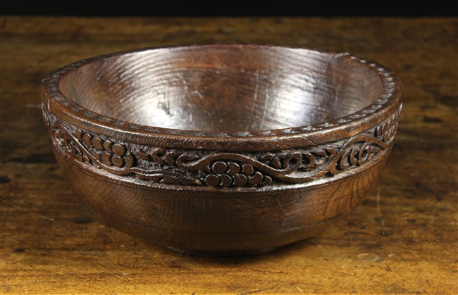 A Turned Oak Bowl with a chip carved edge and a border of carved undulating vine,