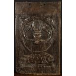 A Good 16th Century English Oak Panel carved with a devil's head in a roundel above a fish,