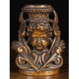 A 17th Century Flemish Walnut Carving of a curly haired cherub's head bearing a basket,