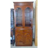 A mahogany bookcase of two glazed doors over two drawers above two cupboard doors raised on plinth