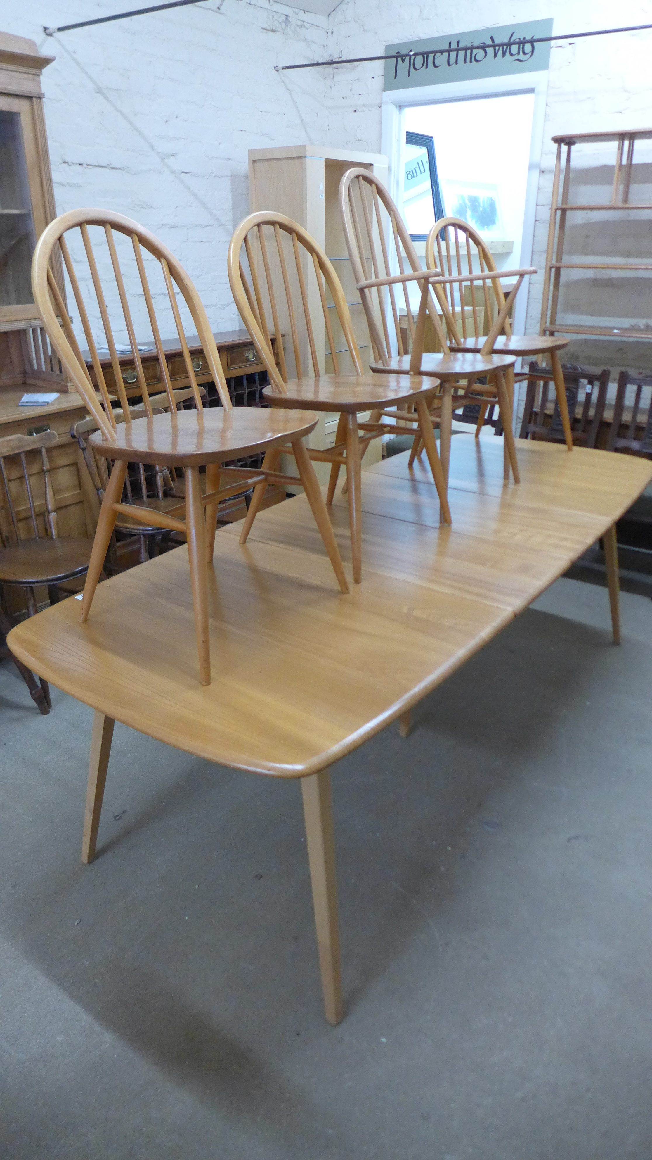 An Ercol blonde elm pullout extending dining table with a hinged central leaf on five tapering legs