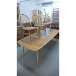 An Ercol blonde elm pullout extending dining table with a hinged central leaf on five tapering legs