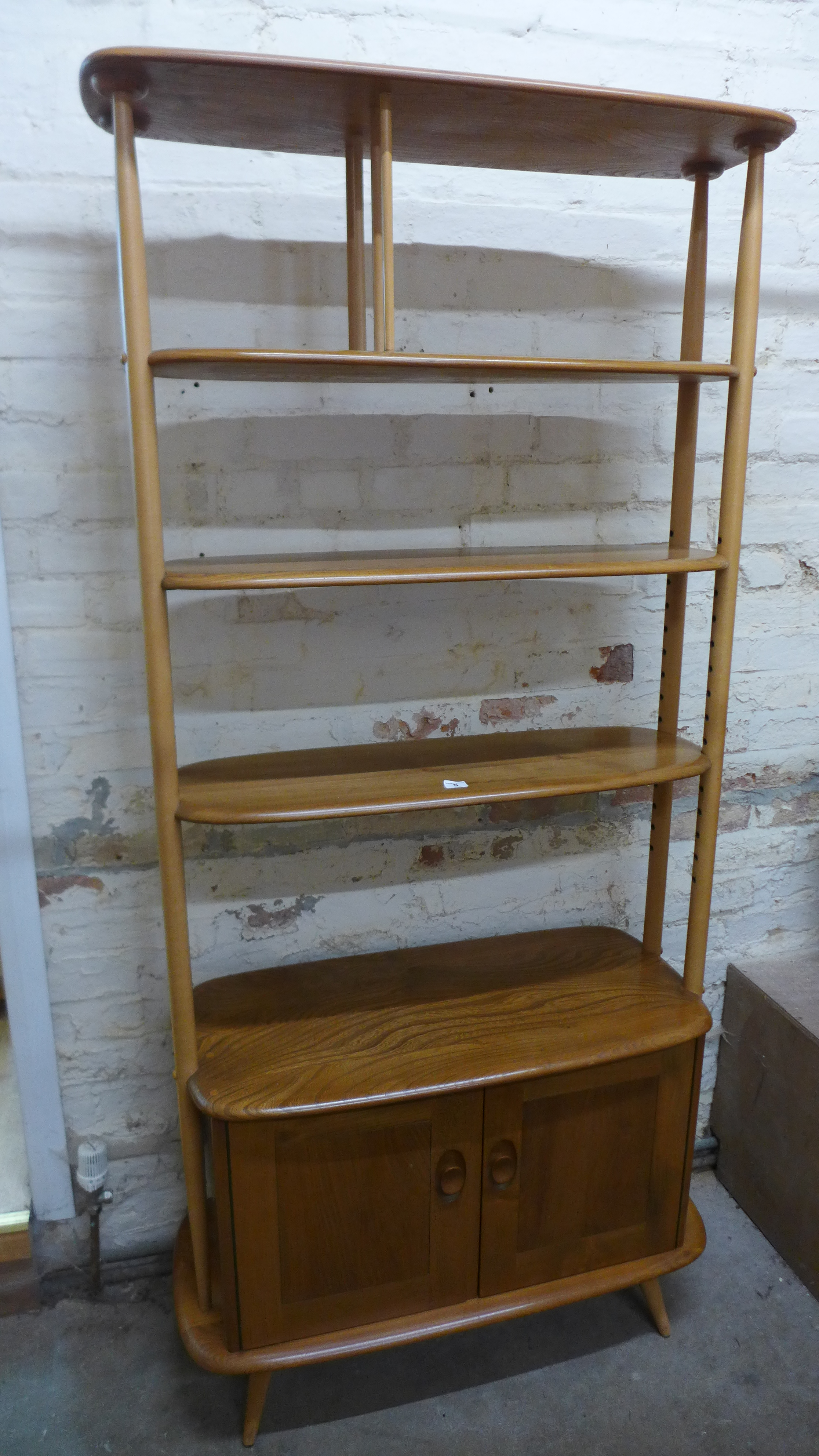 An Ercol blonde elm room divider with two adjustable shelves and two base cupboard doors - Height