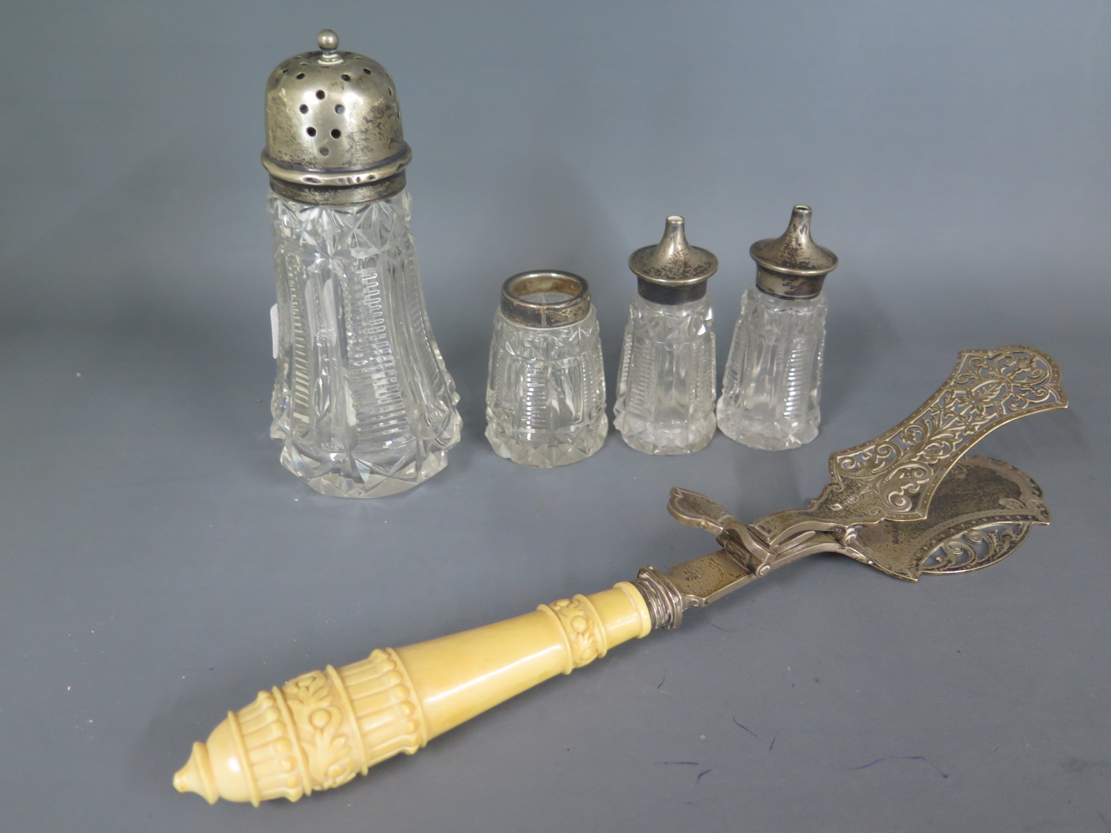 A silver top glass sifter and three glass cruet pieces with silver tops - one piece missing lid,