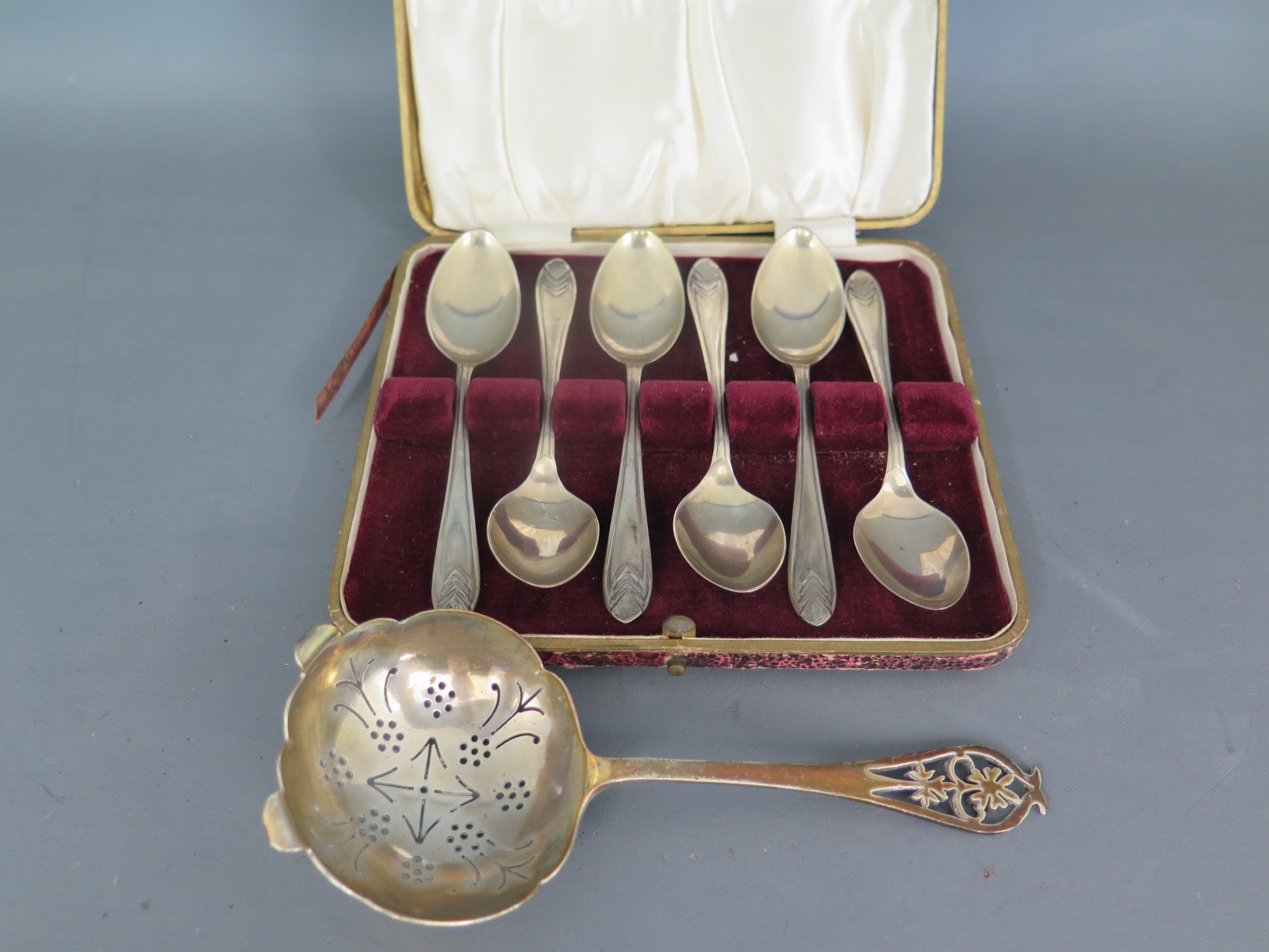 A cased set of silver hallmarked teaspoons and a silver hallmarked strainer spoon 1950 and 1953