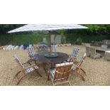 A teak circular garden table with a granite lazy susan,