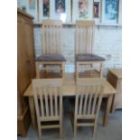 A light oak pull out dining table with one leaf and four chairs with suede seats - in good