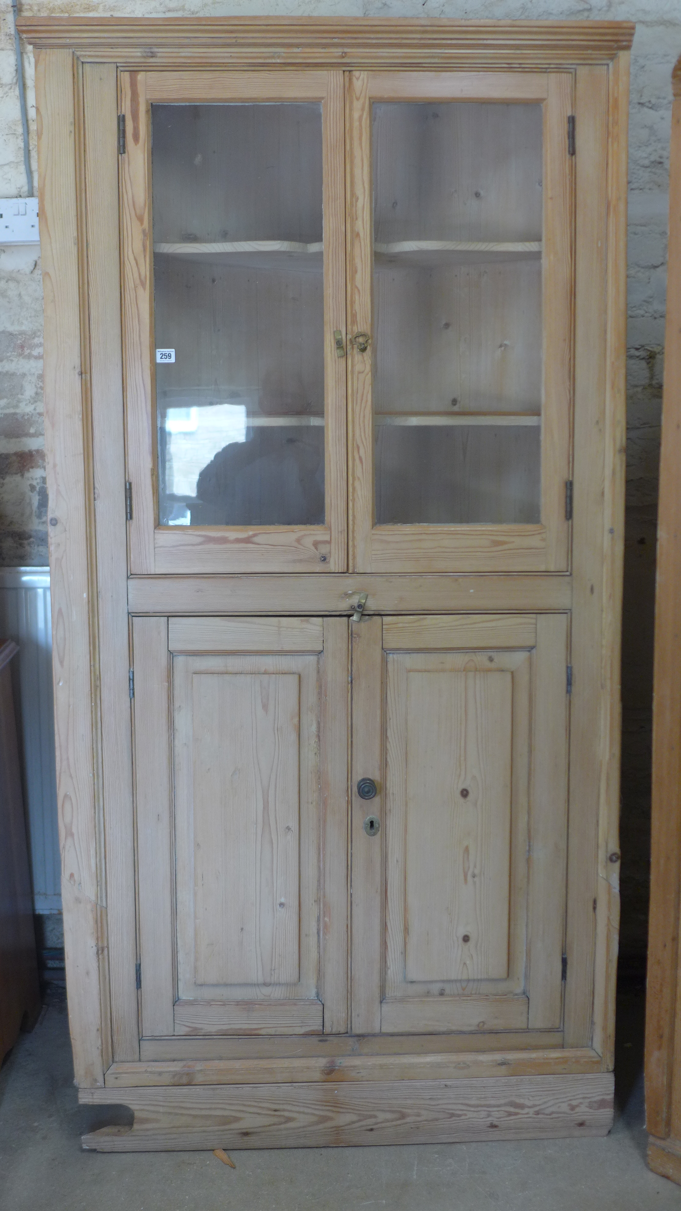 A 19th century stripped pine corner cupboard with two glazed doors above two panelled doors -