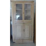 A 19th century stripped pine corner cupboard with two glazed doors above two panelled doors -
