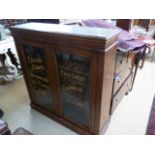 A late 19th century oak bookcase with later advertising sign writing for Charley Browns Ironmongery,