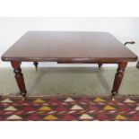 A Victorian wind out dining table with one extra leaf and handle in clean restored condition -