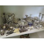 A large selection of silver plated items including flatware, hot water jug, candlesticks,