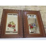 A pair of oak framed bevelled mirrors with fruiting vine design above still life of flowers - 53cm