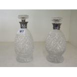 Two cut glass decanters with silver collars