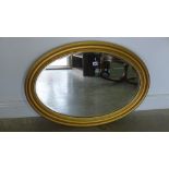 A large oval gilt mirror - 88cm x 63cm