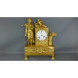 A gilt metal cased mantle clock figures to top with applied decoration,