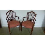 A pair of mahogany framed shield back carvers with overstuffed serpentine fronted seats raised on