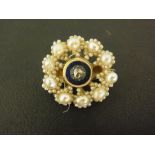 An early 20th century diamond, enamel and seed pearl brooch of snowflake design,