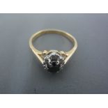 An 18ct yellow gold ring with dark blue oval stone surrounded by six small diamonds - ring size M -