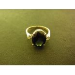 An 18ct yellow gold ring with a central green black stone flanked either size by small diamonds -